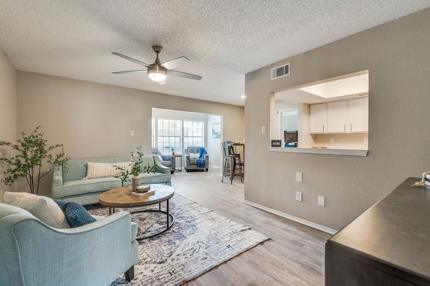 the living room and kitchen of an apartment with couches and a table